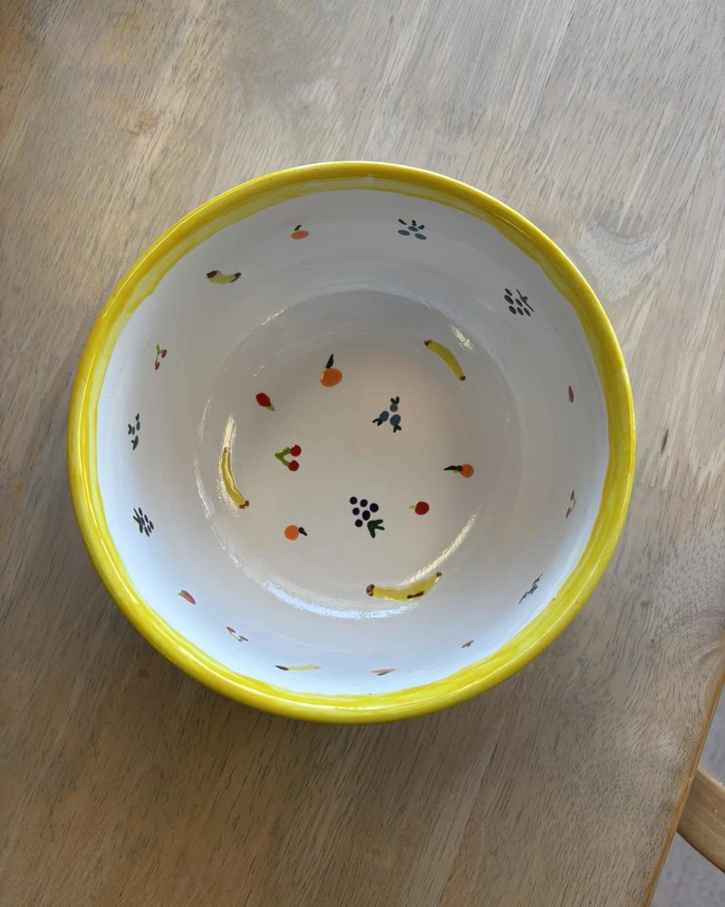 White bowl with a yellow rim and tiny painted fruit